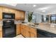 Efficient kitchen design featuring black appliances, wooden cabinets, and bar seating with views to the living room at 7100 N Ocean Blvd. # 221, Myrtle Beach, SC 29572