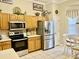Well-lit kitchen with stainless steel appliances, oak cabinets, and tiled flooring at 7471 Balmore Dr. Sw, Sunset Beach, NC 28468