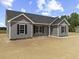 New home with gray siding, black shutters, and a concrete sidewalk and driveway on a sunny day at 825 Highway 67, Loris, SC 29569
