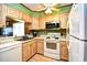 This well-lit kitchen offers white appliances, wood cabinets, and a view through to the living area at 9501 Shore Dr. # D-337, Myrtle Beach, SC 29572