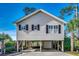 Stilt home features siding, black shutters, and a garage and outdoor entertaining space below at 9671 Stillwater Ct., Myrtle Beach, SC 29572