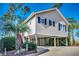 Charming raised beach house with light beige siding, dark shutters and a lush, tropical landscaped yard at 9671 Stillwater Ct., Myrtle Beach, SC 29572