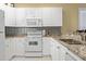Bright kitchen featuring white cabinets, granite countertops, stainless steel sink, and white appliances at 1033 World Tour Blvd. # 101-A, Myrtle Beach, SC 29579