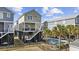 Charming elevated beach house with private pool, lush landscaping, and black wrought iron fence at 132 Garden City Retreat Dr., Murrells Inlet, SC 29576