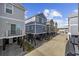 Multiple elevated homes on a concrete street, showcasing unique exterior colors and a consistent architectural style at 132 Garden City Retreat Dr., Murrells Inlet, SC 29576