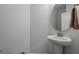 Half-bath features a pedestal sink, a round mirror, and neutral tones, perfect for guests at 1414 Villena Dr., Myrtle Beach, SC 29579