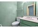 Bathroom with green wallpaper and vanity with one sink, toilet, and towel rack at 2201 S Waccamaw Dr., Murrells Inlet, SC 29576