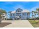 Beautiful blue beach house featuring double garages, multiple decks, and lush tropical landscaping at 2201 S Waccamaw Dr., Murrells Inlet, SC 29576