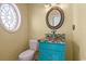 Unique powder room featuring a turquoise vanity with glass bowl sink and round decorative mirror at 2201 S Waccamaw Dr., Murrells Inlet, SC 29576