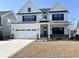 Charming two-story home showcasing a blue front door, white facade, and a two-car garage at 2317 Hazel Way, Longs, SC 29568