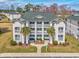 Three-story condo building with white siding, green shutters, and well-maintained landscaping and palm trees at 473 White River Dr. # C, Myrtle Beach, SC 29579