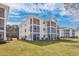 Exterior view of a well-maintained condo building with screened porches and lush lawn at 473 White River Dr. # C, Myrtle Beach, SC 29579