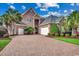 Stately brick home with a brick driveway, lush landscaping and a two-car garage at 707 Compass Pointe Dr, North Myrtle Beach, SC 29582