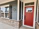 Inviting home entrance featuring a vibrant red front door, brick accents, and white trim at 9021 Aria Way, Longs, SC 29568