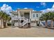 Beautiful elevated home with stone accents, dual garages, inviting stairs, and lush palm trees in the front yard at 1004 Marsh View Dr., North Myrtle Beach, SC 29582