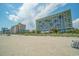 Beachfront view of the condo complex with sand, dunes, and beach umbrellas at 1105 S Ocean Blvd. # 220, Myrtle Beach, SC 29577