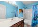 Bright bathroom with blue walls, a sink with dark wood cabinets, and a shower with a blue curtain at 125 Dayglow Dr., Loris, SC 29569