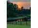 Scenic backyard view with pond, black metal fence, trees, and a colorful sunset at 1330 Reflection Pond Dr., Little River, SC 29566