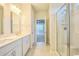 Bathroom with dual vanities, tile floor, and a glass door shower, next to open doorway to the bedroom at 1330 Reflection Pond Dr., Little River, SC 29566