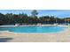 Community pool surrounded by tables, chairs, and green trees at 1330 Reflection Pond Dr., Little River, SC 29566