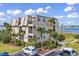 Exterior view of building with palm trees, green lawn and partial parking area under a blue cloudy sky at 1582 S Waccamaw Dr. # 44, Murrells Inlet, SC 29576