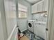 Compact laundry room with a front load washer, dryer, overhead cabinets, and a small window at 1651 Fairforest Ct., Conway, SC 29526