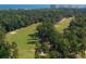 Aerial view of a lush golf course lined with trees, with ocean and buildings in the distance at 2052 Copper Creek Ct., Longs, SC 29568