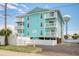 Turquoise condo with three stories, white railings, palm tree, and asphalt drive on a clear day with a blue sky at 212 58Th Ave. N # 1C, North Myrtle Beach, SC 29582