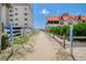 Picturesque public walkway leading to the beach with clear signage, surrounded by lush greenery and beautiful architecture at 212 58Th Ave. N # 1C, North Myrtle Beach, SC 29582