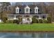 A charming two-story home features a manicured lawn, covered porch, and pergola near the pond at 2325 Highway 111, Little River, SC 29566