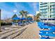 Sandy beach with lounge seating, tables and chairs, and blue umbrellas at 300 N Ocean Blvd. # 1026, North Myrtle Beach, SC 29582