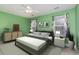 This bedroom boasts green walls, a ceiling fan, and large windows with decorative curtains at 310 Junco Circle, Longs, SC 29568