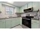 Well-lit kitchen featuring stainless steel appliances, mint cabinets, and a classic tile backsplash at 3901-B Birchwood St., North Myrtle Beach, SC 29582