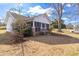 Side view of a quaint single story home with a screened porch and mature trees on a sunny day at 5092 Harrelson Ave., Loris, SC 29569