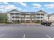 Three-story condo building with white balconies, a parking lot and some landscaping at 5801 Oyster Catcher Dr. # 724, North Myrtle Beach, SC 29582