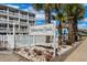 Whispering Sands sign nestled among palm trees, with a white picket fence and community pool in the background at 625 N Waccamaw Dr. # 102, Murrells Inlet, SC 29576