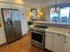Bright kitchen featuring stainless steel appliances, white cabinets, and wood flooring with views of the dining area at 671 Norris Dr., Pawleys Island, SC 29585