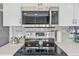 Close up of stainless steel microwave and range with tile backsplash and light countertops at 8560 Queensway Blvd. # 1206, Myrtle Beach, SC 29572