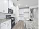 Modern kitchen boasts white cabinets, granite countertops, stainless steel appliances, and tile backsplash at 8720 High Banks Way, Longs, SC 29568