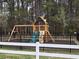 Playground featuring a swing set, climbing wall, slide, and mulch base behind a fence at 9903 Conifer Ln., Murrells Inlet, SC 29576
