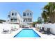 Inviting backyard pool with lounge chairs, white picket fence, and coastal homes under a bright blue sky at 113-B 10Th Ave. S, Surfside Beach, SC 29575