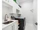 Bright laundry room with white cabinetry, a modern sink, and a new dark-colored washer and dryer set at 1217 Bentcreek Ln., Myrtle Beach, SC 29579