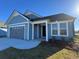Beautiful blue home featuring an attached garage, a covered porch, and manicured lawn at 1249 Crested Iris Way, North Myrtle Beach, SC 29582