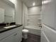 Bright bathroom with a shower-tub combo, white vanity, and dark tile flooring at 1253 Crested Iris Way, North Myrtle Beach, SC 29582