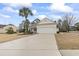 View of single story home with tan siding, palm tree and long driveway leading to a two car garage at 14 Cobblestone Dr., Pawleys Island, SC 29585