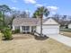 Charming single-story home with a well-manicured lawn, palm tree, inviting porch, and attached garage at 14 Cobblestone Dr., Pawleys Island, SC 29585