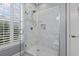 Modern glass enclosed shower with white tile, a built-in niche, and plantation shutters at 14 Cobblestone Dr., Pawleys Island, SC 29585