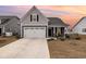 Charming home featuring a two-car garage, inviting front porch and manicured lawn set against a picturesque sunset sky at 1881 Moonseed Dr., Longs, SC 29568