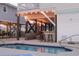 A clear swimming pool surrounded by a patio area, an outdoor bar and comfortable lounge furniture at 225-B Dogwood Dr. N, Murrells Inlet, SC 29576