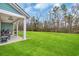 Picturesque backyard with a large lawn, mature trees, and covered patio space at 2418 Goldfinch Dr., Myrtle Beach, SC 29577